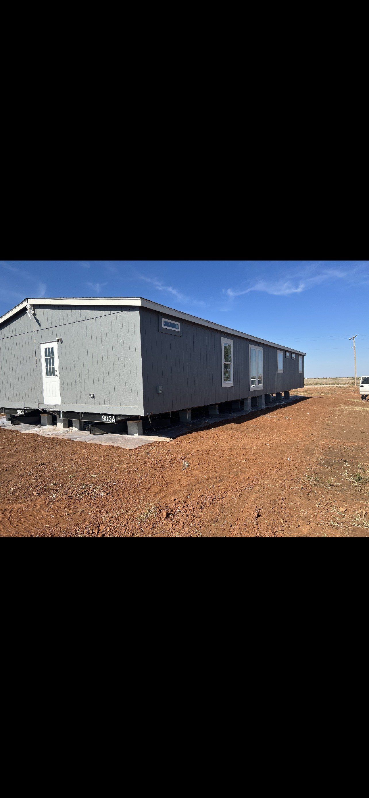 Gray mobile home on blocks.
