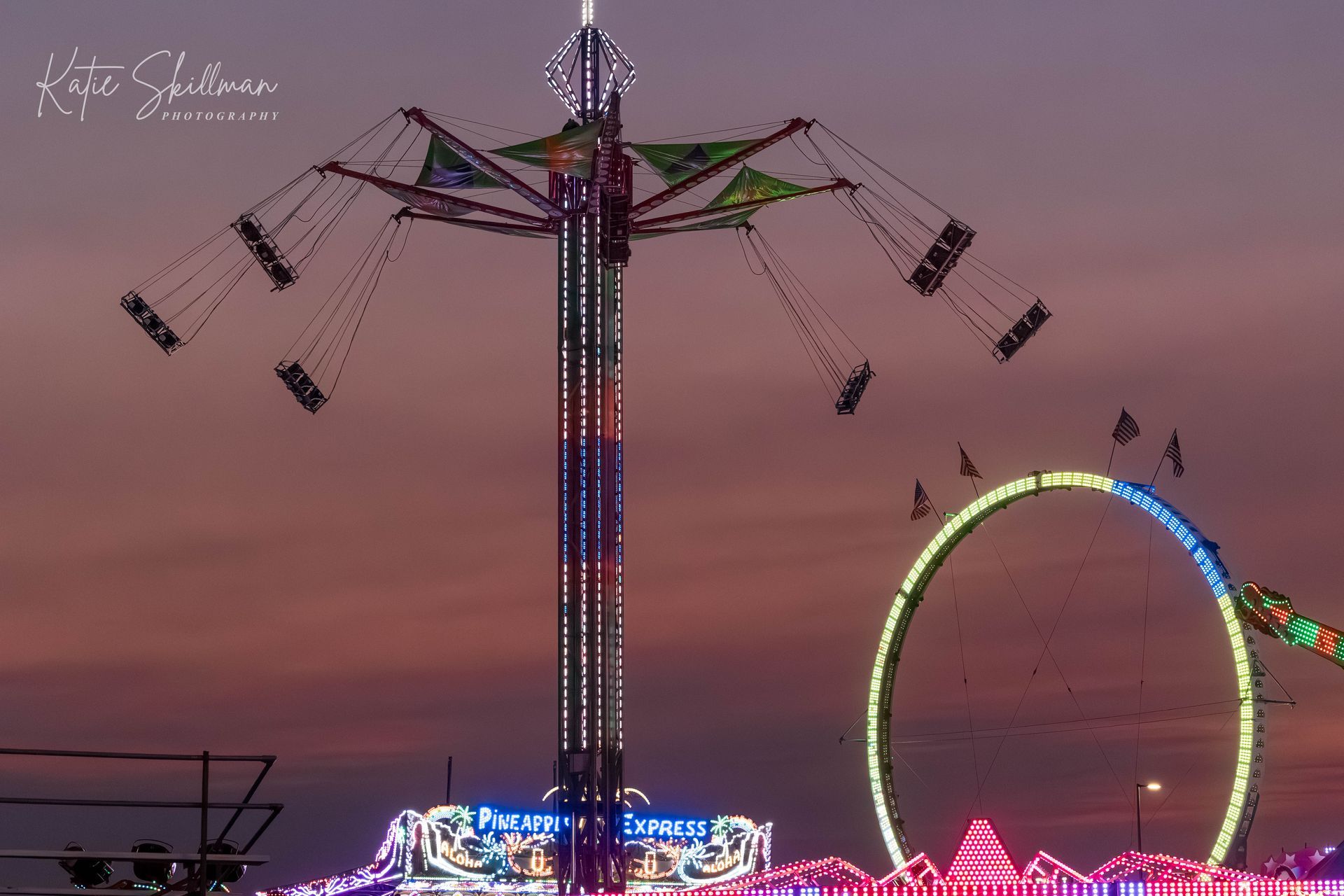 a ferris wheel is silhouetted against a cloudy sky at sunset .