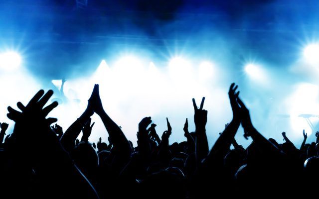 a man is playing a guitar on a stage in front of a ferris wheel .
