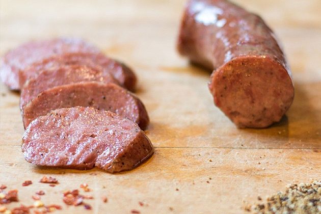 Sliced sausage on a wooden cutting board, with one cut end facing the camera.