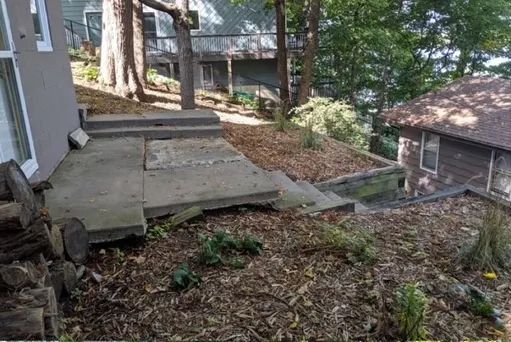 A concrete patio with stairs leading up to a house on a hill