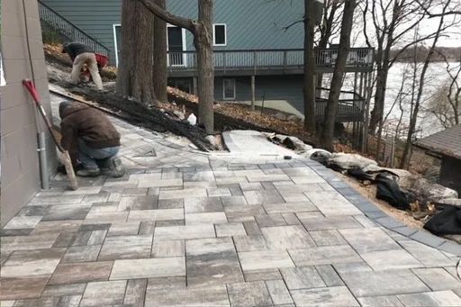 A man is kneeling down on a patio next to a house