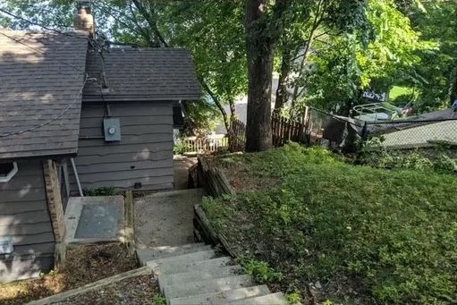 A house with stairs leading up to it and trees in the background