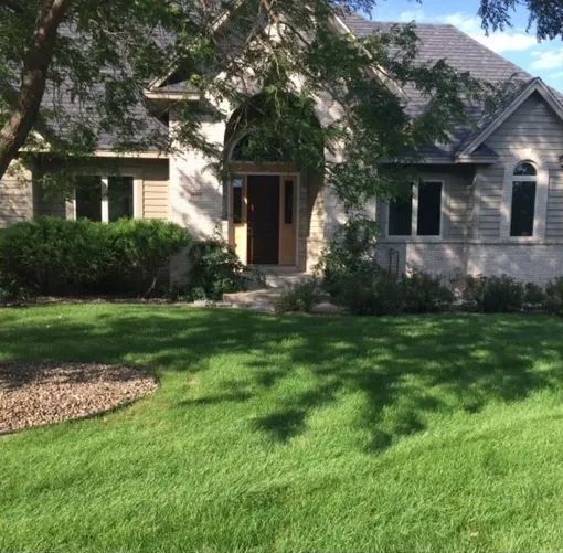 A house with a lush green lawn in front of it