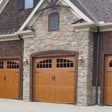Stone facade garage with three brown wooden doors.