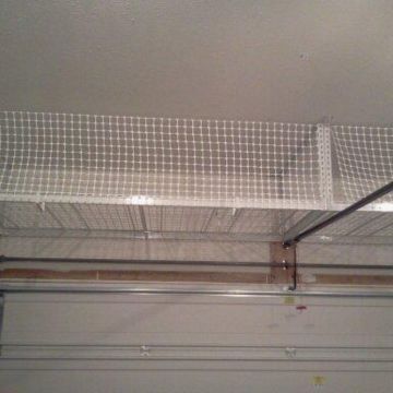 White netting installed above a garage door, possibly for storage.