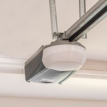 Garage door opener mounted on a white ceiling, with a visible light and chain.