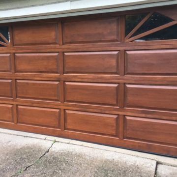 Brown paneled garage door with decorative window inserts.