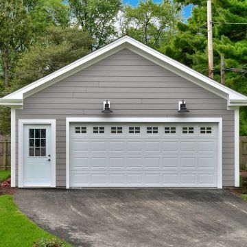 Gray garage with white trim and door, two sconces, and a driveway.