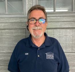 Older man with gray hair and beard, smiling, looking to the side.