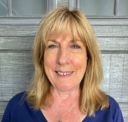 Woman with braided hair and glasses smiles.