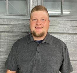 Woman smiling, hand near face. Indoor setting with soft lighting.