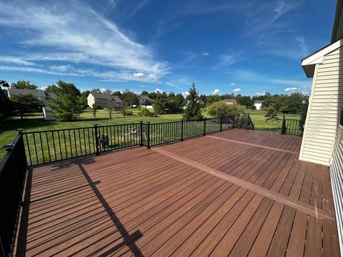 Wooden deck overlooking a grassy neighborhood under a blue sky