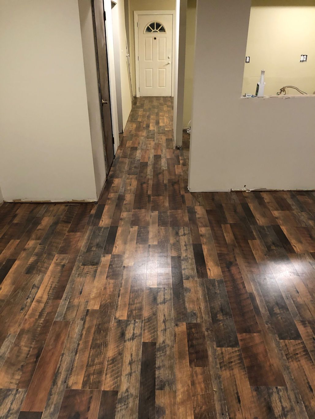 Empty hallway with dark wood flooring and a white door at the end