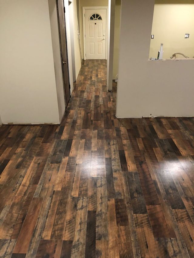 Empty hallway with dark wood floors, white walls, and a closed door at the end