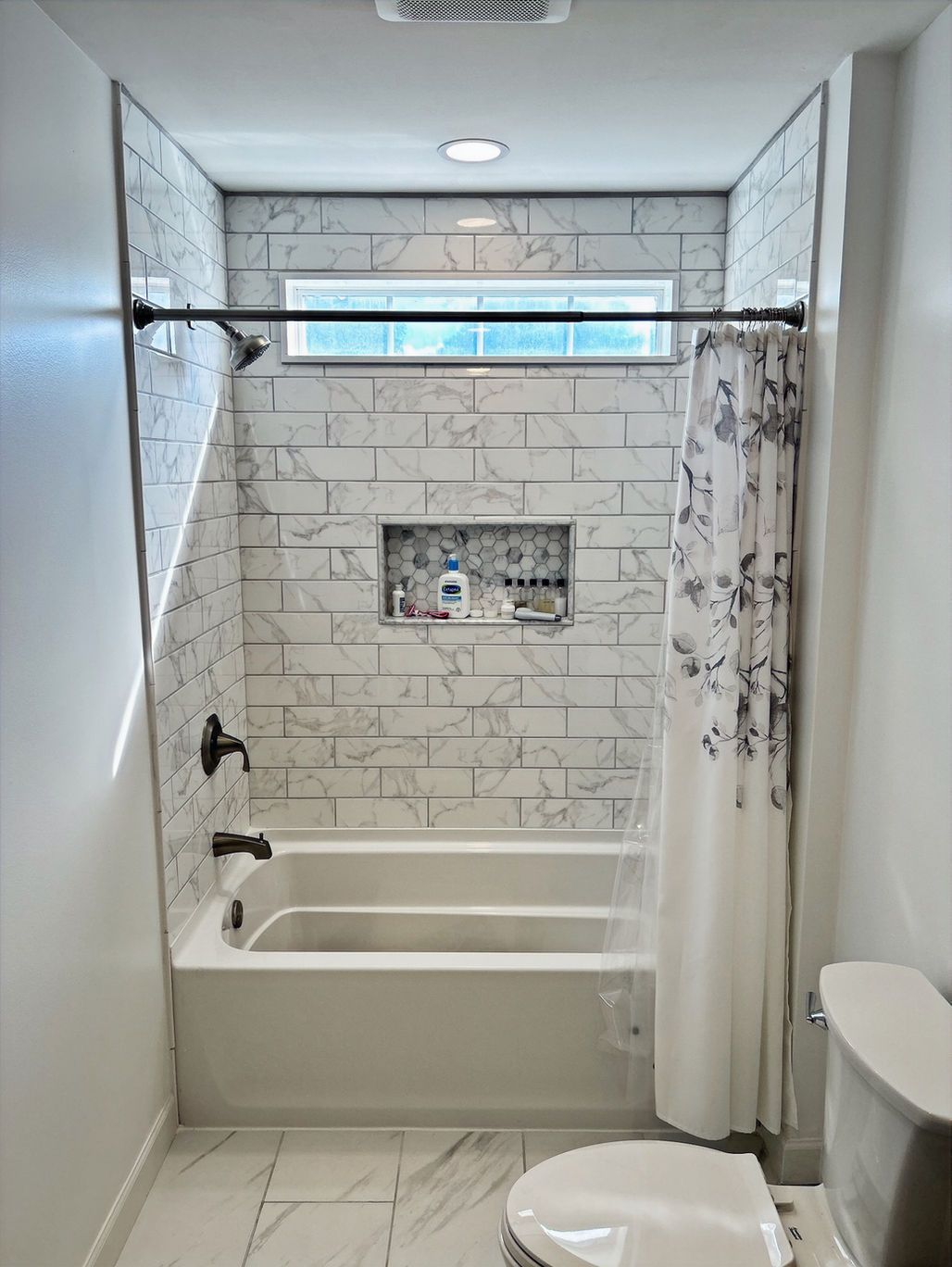Small bathroom with bathtub, shower curtain, toilet, and white tile walls
