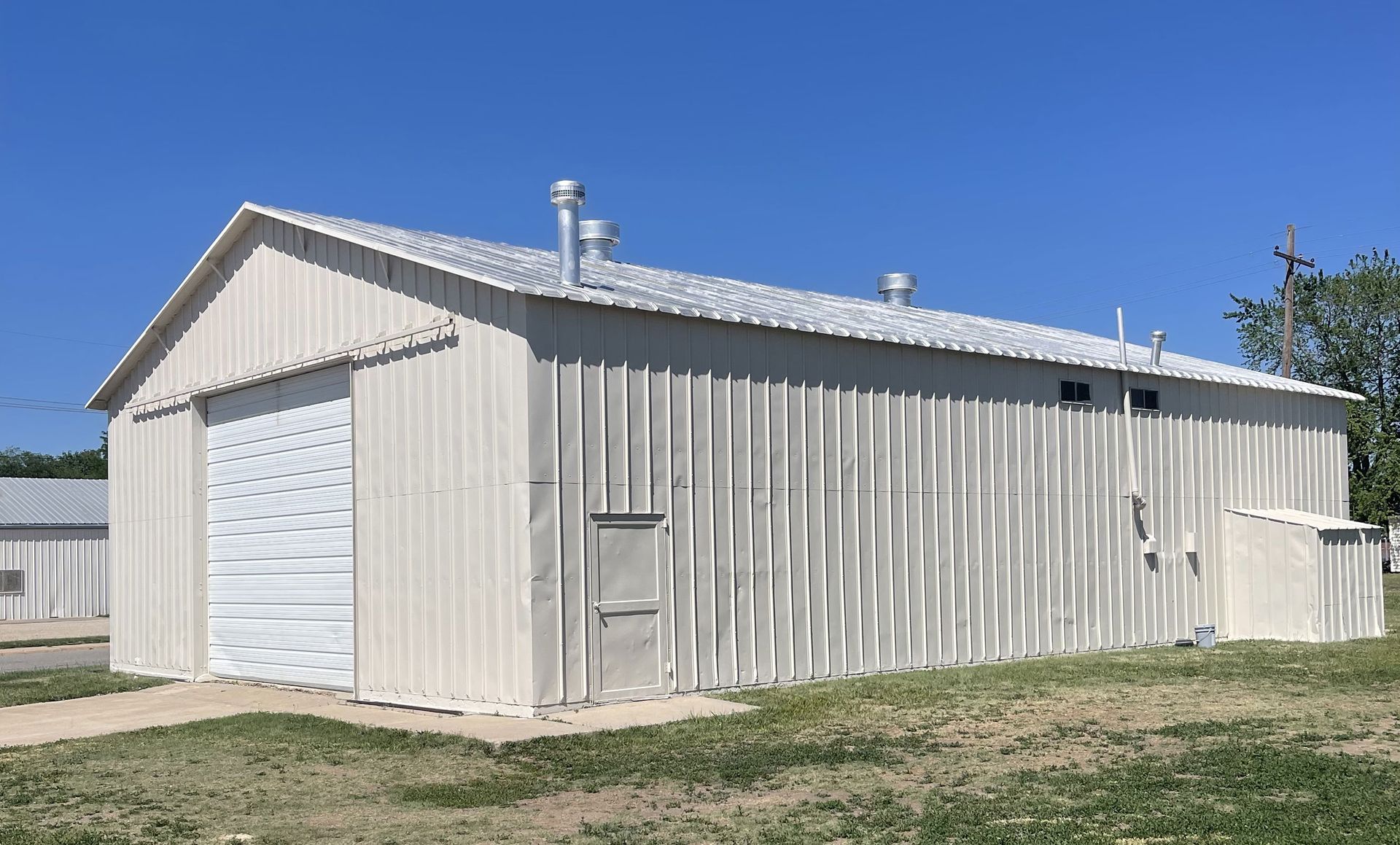 A large white barn is sitting in the middle of a grassy field