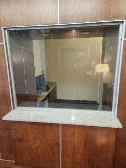 A customer service window featuring a glass partition, a granite counter, and wood-paneled walls. 