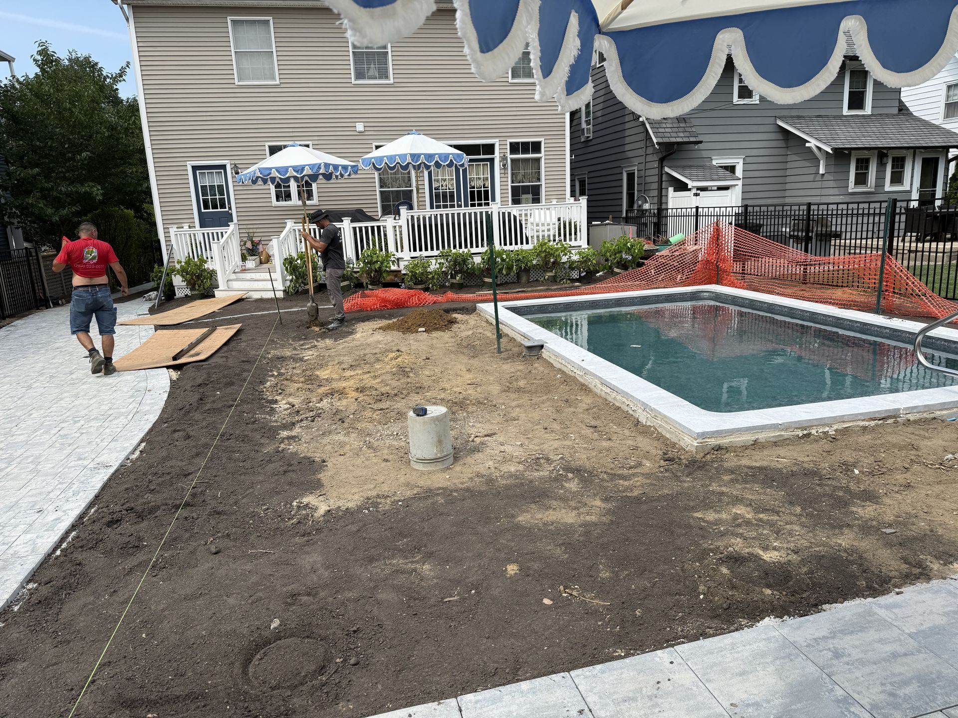 Backyard with a small pool under construction beside a house and patio seating area