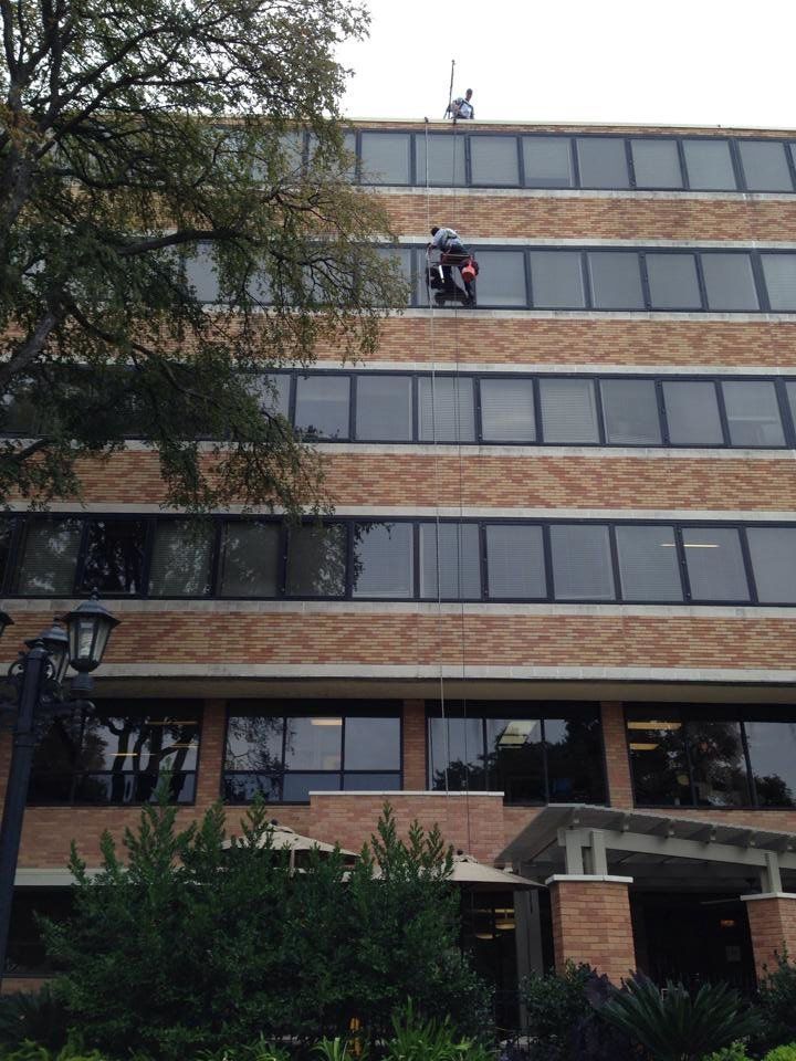 A man is cleaning the windows of a large brick building