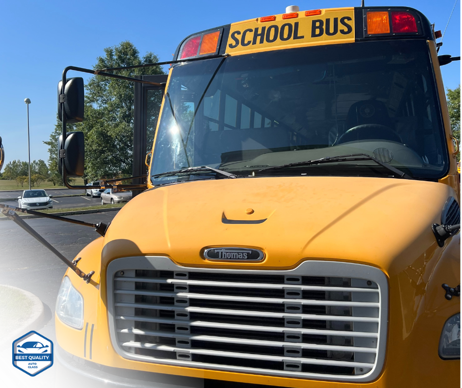 Yellow school bus with flashing lights parked on a road, front view