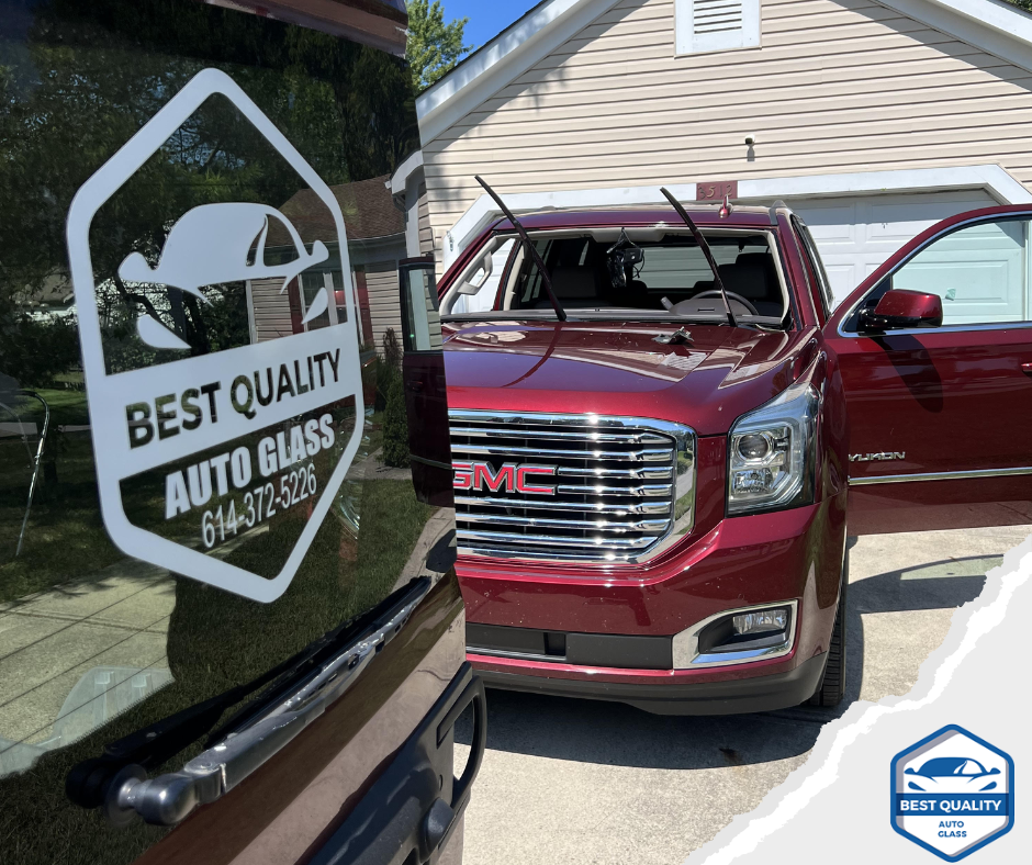 Red GMC SUV parked beside a vehicle with “Best Quality Auto Glass” logo on the window