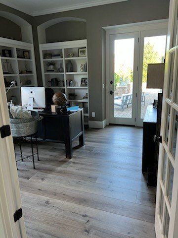 Home office with built-in shelves, desk, and a bright doorway to a patio.