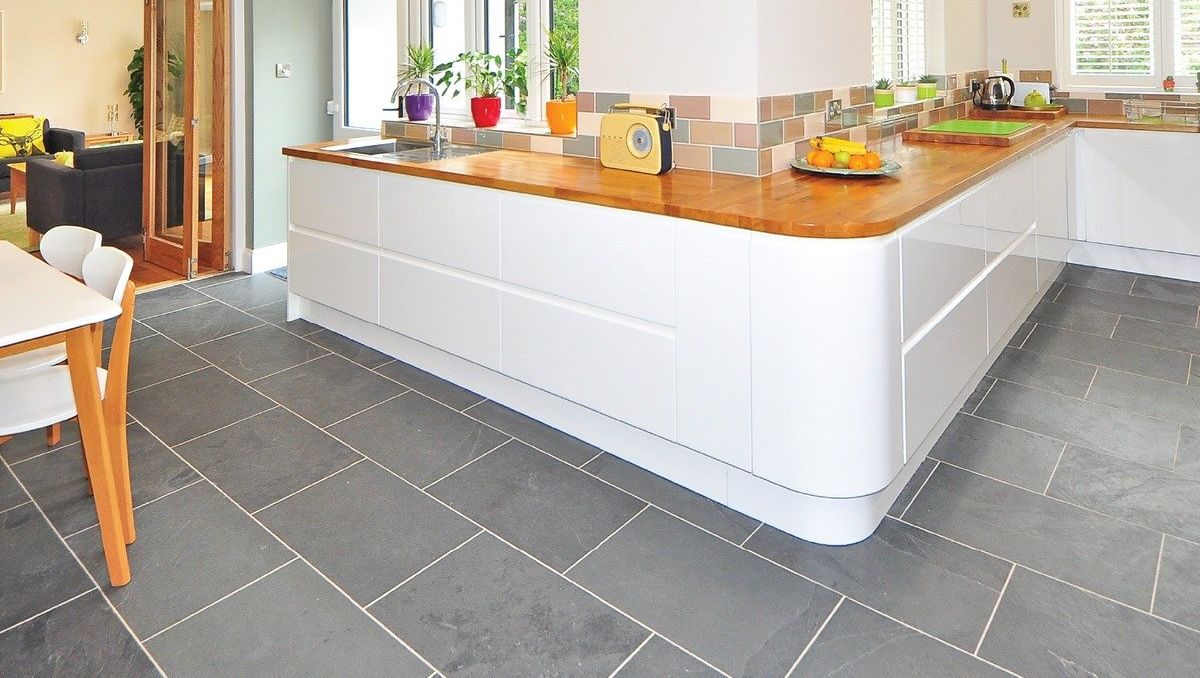 Bright modern kitchen with white island, wooden countertop, tiled floor, and large window