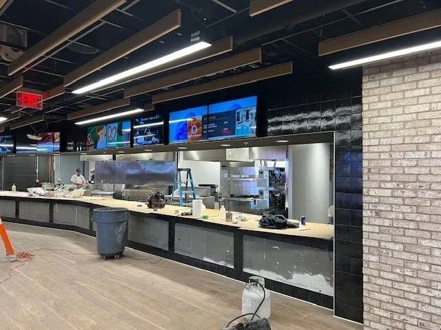 Empty restaurant counter with digital menu screens and stainless-steel prep area
