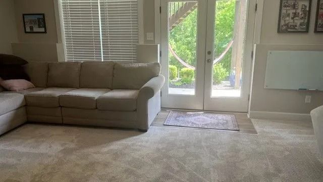 Bright living room with beige sectional sofa, carpet, and glass doors opening to a patio.