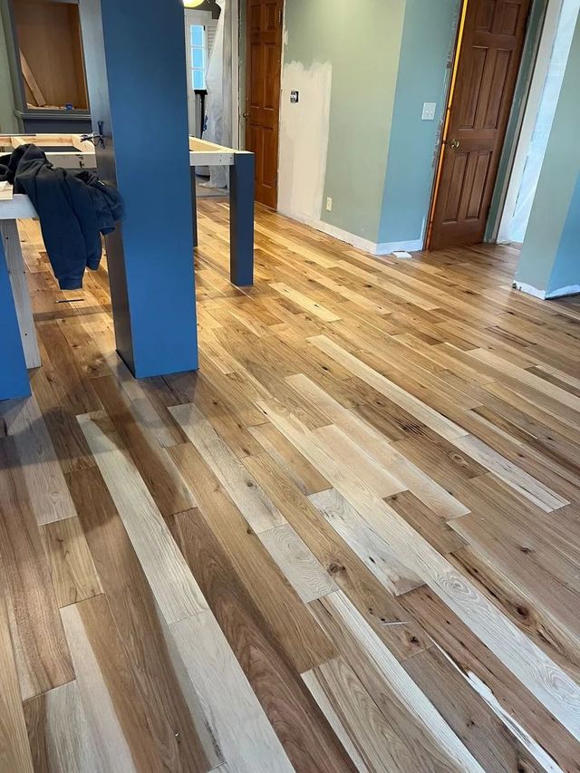 Empty room with light wood floors, blue walls, and a table edge on the left