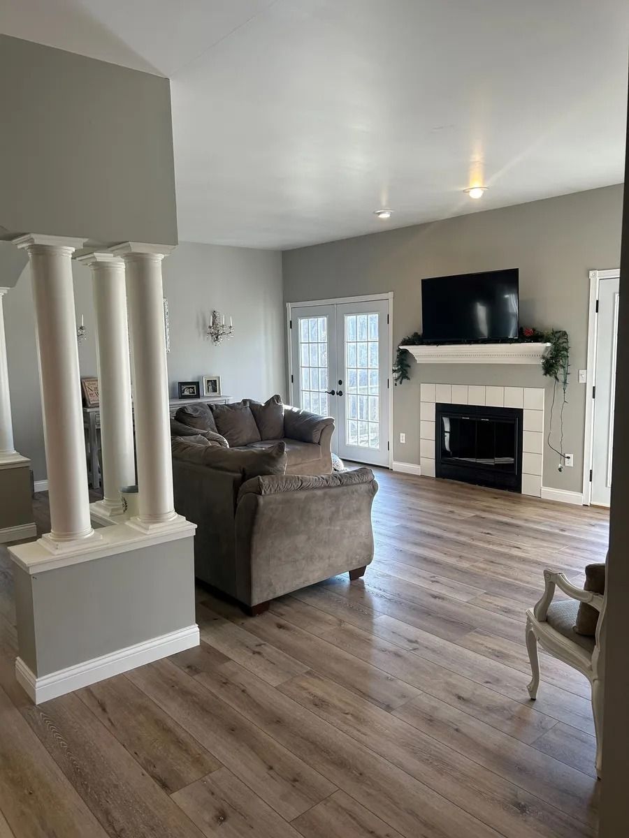 Bright living room with gray sofa, fireplace, wall-mounted TV, and wood floors