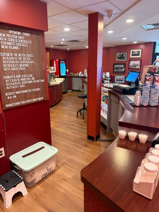 Cozy café interior with red walls, wooden floors, counter seating, and a menu board on the left.