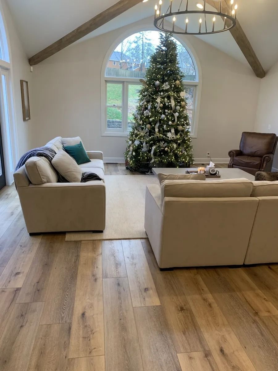 Living room with Christmas tree, beige sofas, and a large arched window
