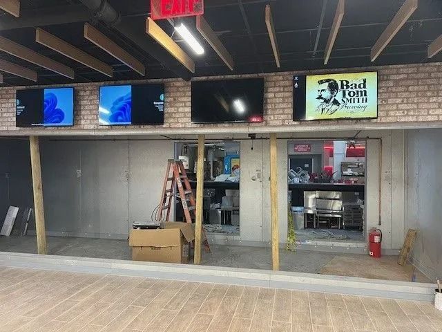 Empty bar interior with TVs, exposed ceiling beams, and an open service counter area