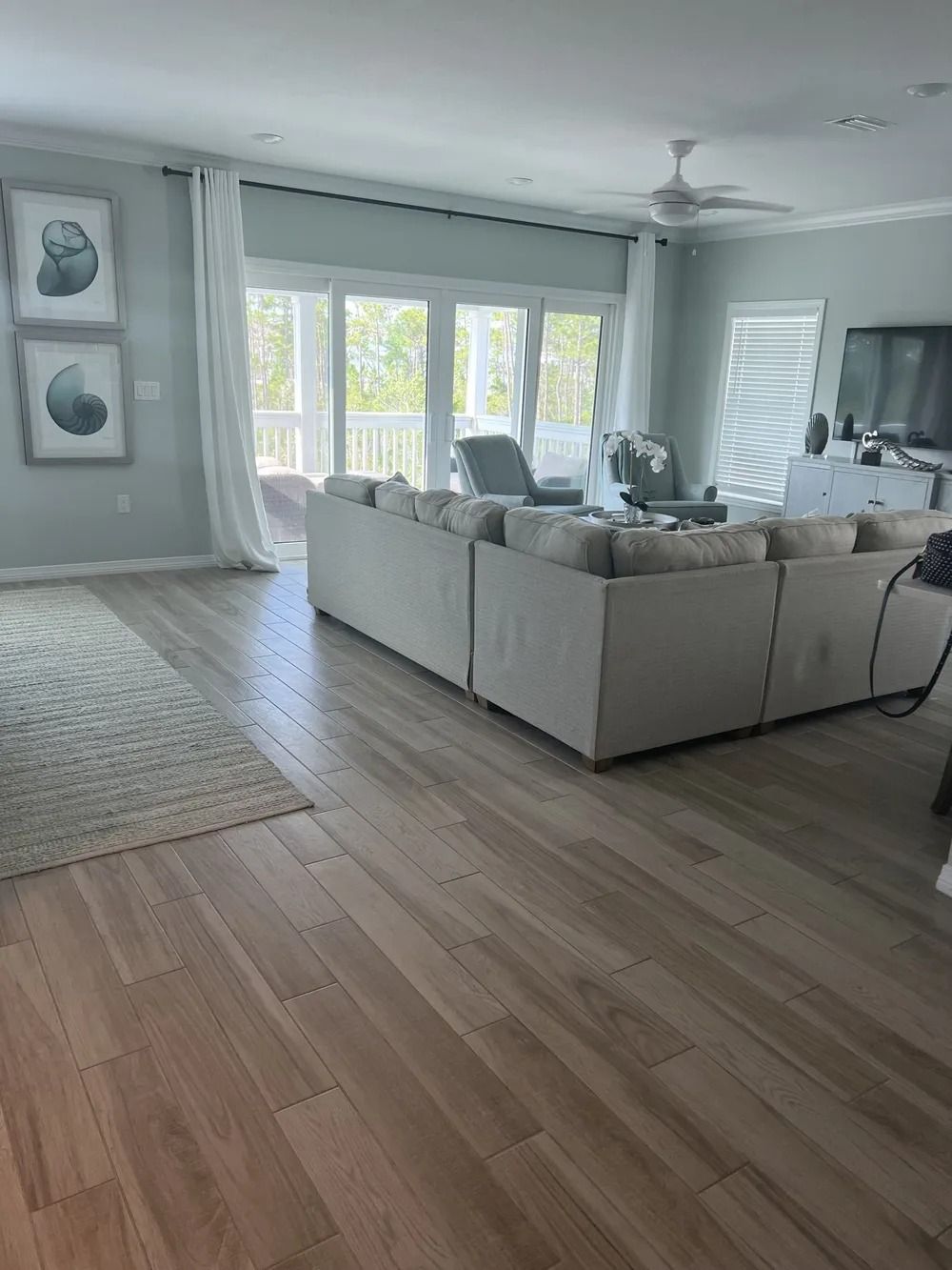 Bright living room with a white sectional sofa, large windows, and light wood floors