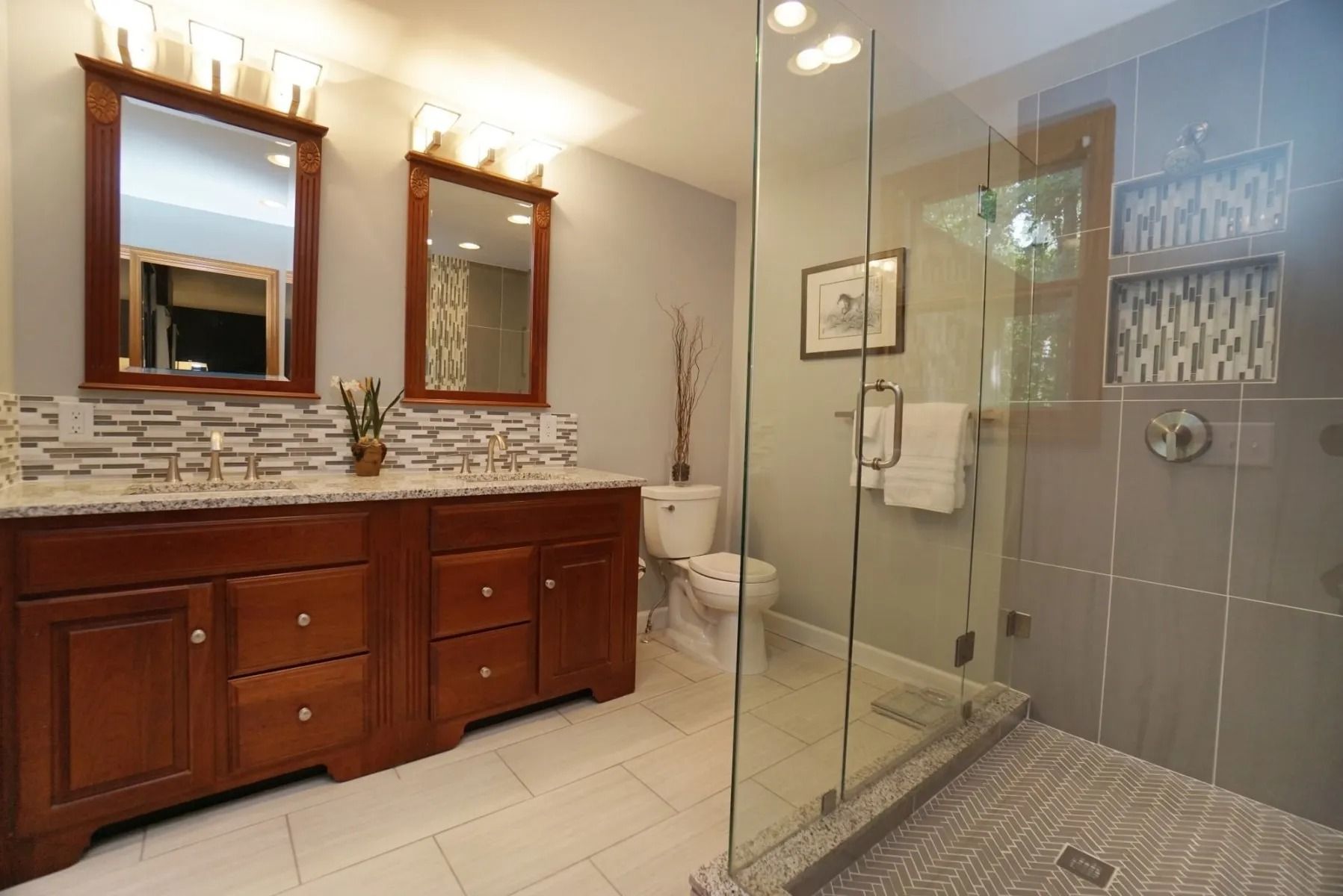 Bathroom with double vanity, mirrors, and glass-enclosed shower in beige and gray tones