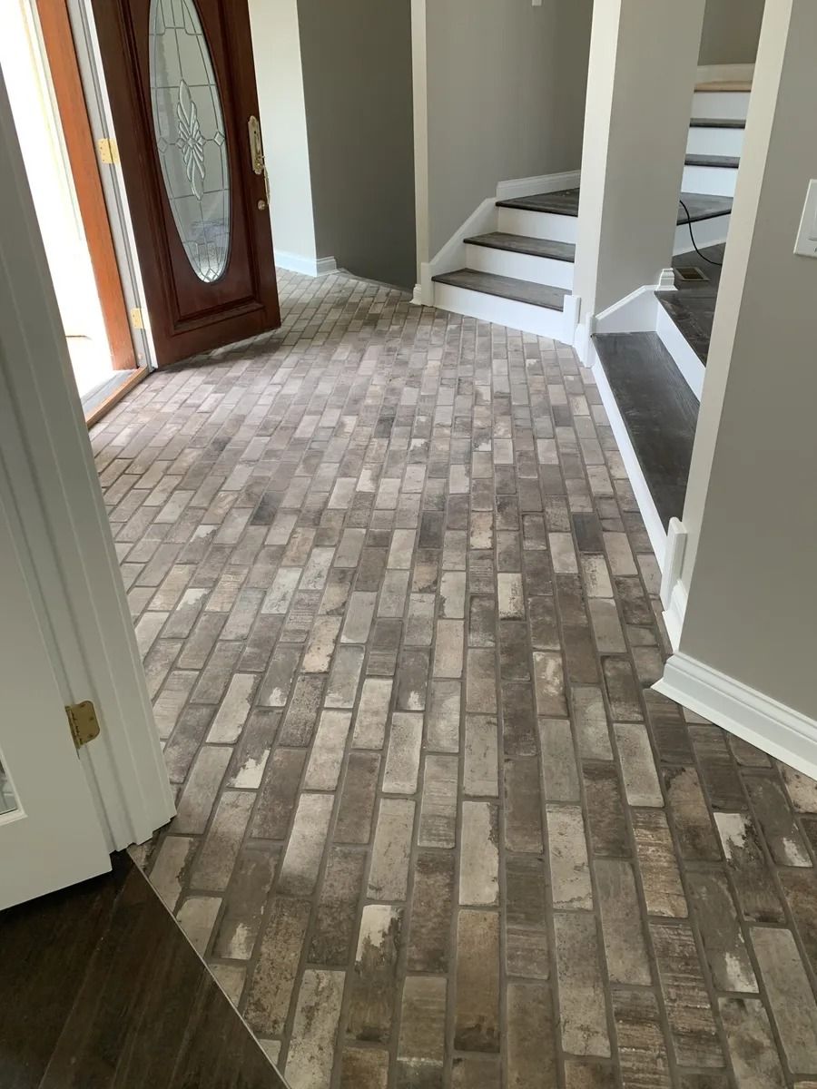 Empty entryway with light tile floor, front door, and stairs leading up.
