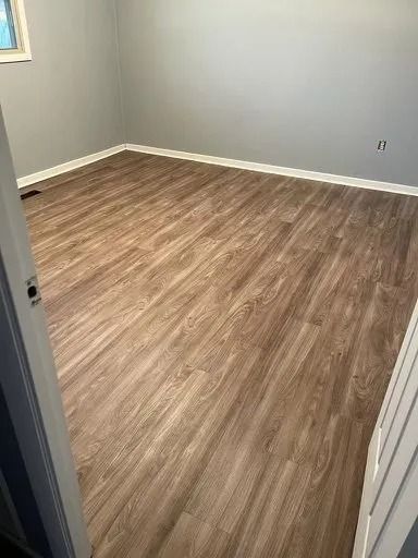 Empty room with gray walls and wood-look flooring, viewed from the doorway
