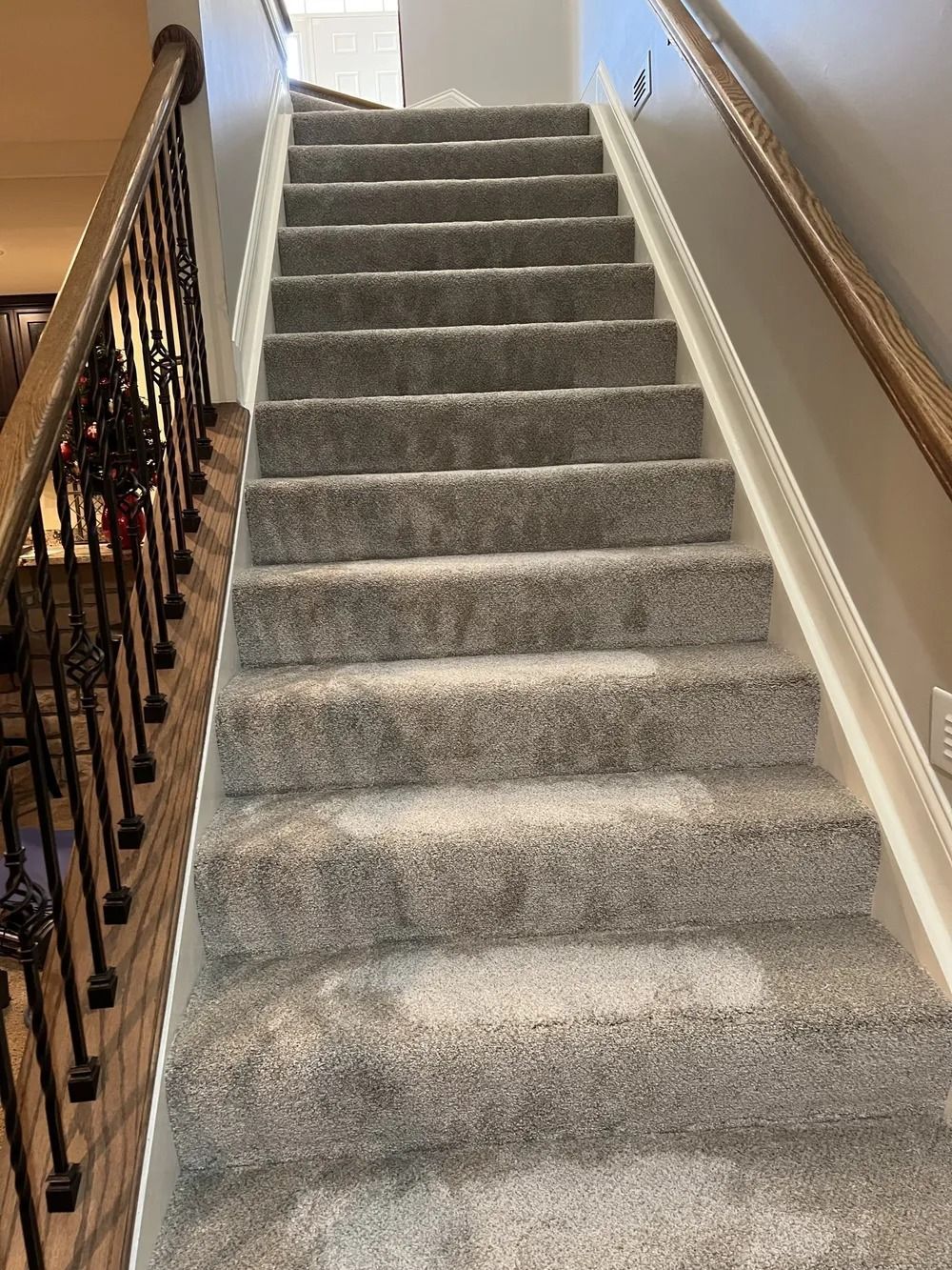 Carpeted staircase with wooden banister and beige walls in a home interior