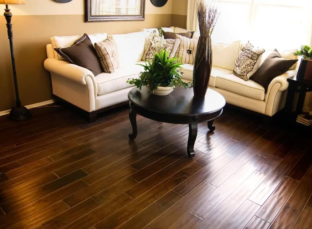 Bright living room with two beige sofas, a round dark coffee table, and dark hardwood floors