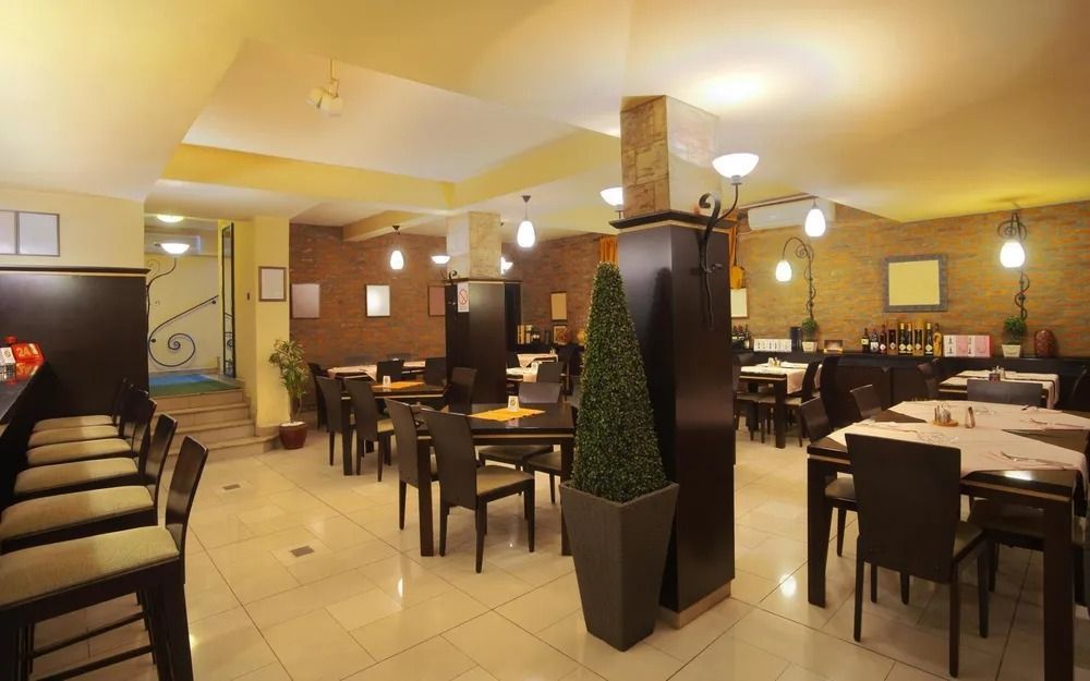 Warmly lit restaurant dining room with empty tables, chairs, and a central decorative pillar