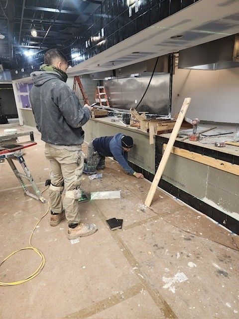Workers installing equipment in a commercial kitchen under construction