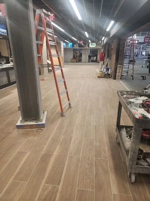 Interior of a store under construction with ladders, tools, and unfinished flooring