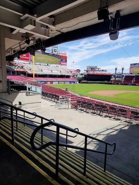 Empty baseball stadium seats and field viewed from a shaded concourse