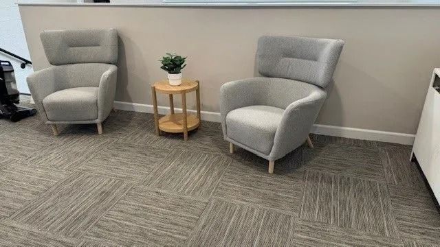 Two gray armchairs with a small round table and plant in a modern waiting area