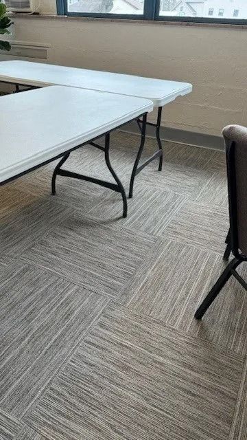 Empty conference room with folding tables and chairs on patterned carpet.