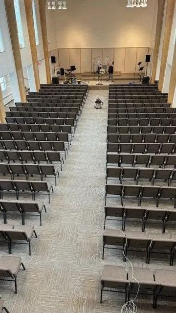 Empty auditorium with rows of chairs facing a stage and central aisle.