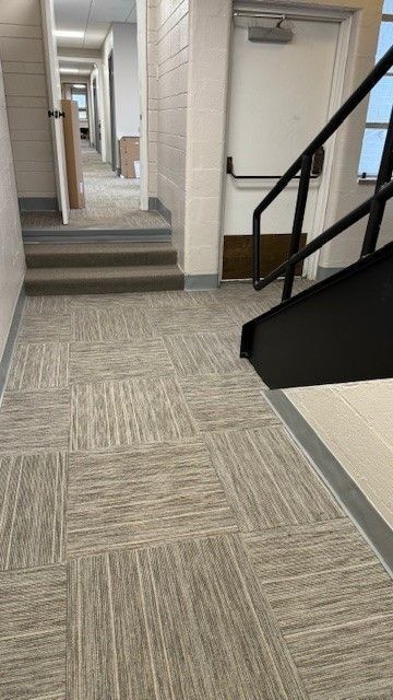 Apartment hallway with carpet, stairs, and black handrails