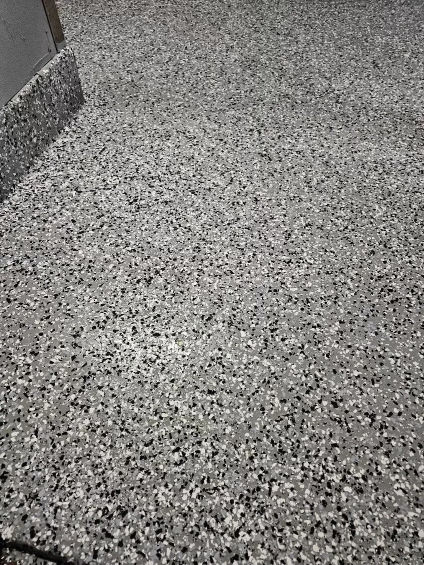 Gray speckled carpeted floor in a corner near a wall and baseboard